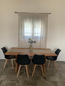 una mesa de comedor con sillas y un jarrón de flores en Eucalyptοs house, en Lefkogeia