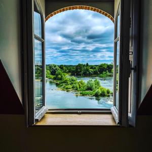 een open raam met uitzicht op een rivier bij Logis Hôtel Le Relais Louis XI in Meung-sur-Loire