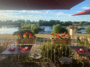 a patio with tables and chairs and a view of a river at Logis Hôtel Le Relais Louis XI in Meung-sur-Loire