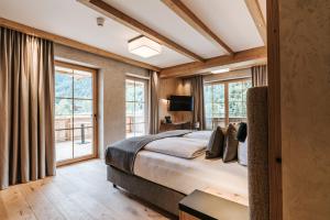 a bedroom with a large bed and windows at NOVA Moments Boutique Hotel in Pertisau