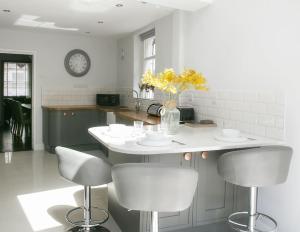 a kitchen with a table with chairs and a vase of flowers at St Magnus House, Fabulous Harrogate town house in Harrogate