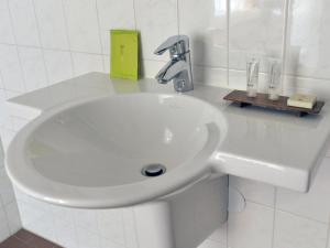 a white sink in a white tiled bathroom at Hotel De Brabantse Biesbosch in Werkendam +36 photos