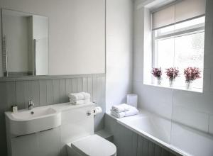 a bathroom with a toilet and a sink and a window at St Magnus House, Fabulous Harrogate town house in Harrogate