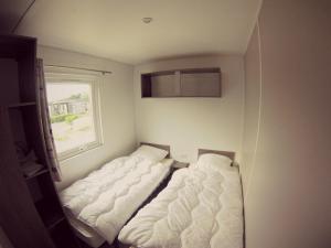 zwei Betten in einem kleinen Zimmer mit Fenster in der Unterkunft Village vacances & camping de Gruissan in Gruissan + 35 Fotos