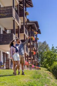 a man and a woman standing in front of a building at Hotel Arcobaleno in Fai della Paganella