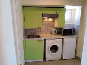 - une cuisine avec des placards verts et un lave-linge dans l'établissement orange, à Ialyssos