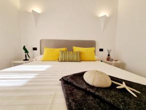 - une chambre avec un grand lit blanc et des oreillers jaunes dans l'établissement STAZZO SAN TEODORO IL GINEPRO, à San Teodoro