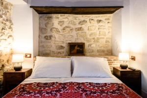 a bedroom with a stone wall with a bed and two lamps at LaVistaDeiSogni La Perla in SantʼIona