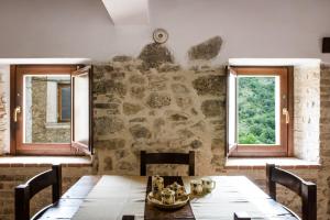 ein Esszimmer mit einem Tisch und 2 Fenstern in der Unterkunft LaVistaDeiSogni La Perla in SantʼIona