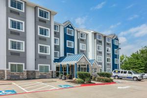 un gran edificio de apartamentos con un coche aparcado en un aparcamiento en Microtel Inn & Suites by Wyndham Austin Airport en Austin