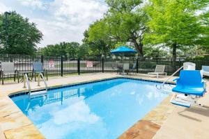 une piscine avec des chaises bleues et une clôture dans l'établissement Microtel Inn & Suites by Wyndham Austin Airport, à Austin