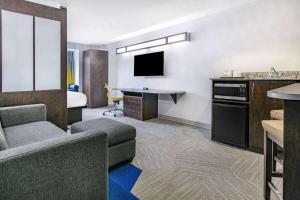 Habitación de hotel con sofá y escritorio con TV. en Microtel Inn & Suites by Wyndham Austin Airport en Austin