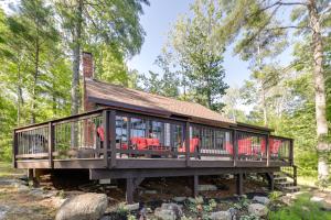 una casa con terraza en el bosque en Waterfront Maine Vacation Rental with Private Dock, en Orono