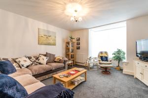 a living room with a couch and a tv at Birkdale boutique Apartment in Southport