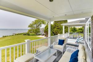 um alpendre com mobiliário branco e vista para a água em Waterfront Massachusetts Vacation Rental with Deck em Little Compton
