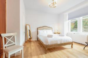 um quarto branco com uma cama e uma cadeira em Murray Place - Central 2 Bed Apt em St. Andrews