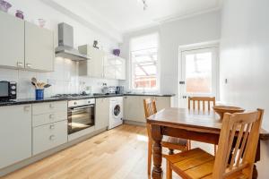 uma cozinha com armários brancos e uma mesa de madeira em Murray Place - Central 2 Bed Apt em St. Andrews
