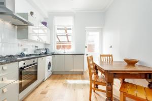 cocina blanca con mesa de madera y comedor de madera en Murray Place - Central 2 Bed Apt en St Andrews