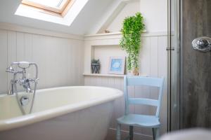 a bathroom with a tub and a blue chair at Seaview House - A Traditional Home by the Beach in Nairn