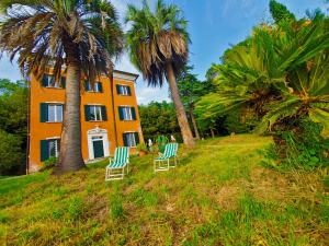 dos sillas frente a una casa con palmeras en Villa De Benedetti en Sarzana