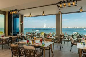 ein Restaurant mit Tischen und Stühlen und Meerblick in der Unterkunft Aloft Palm Jumeirah in Dubai