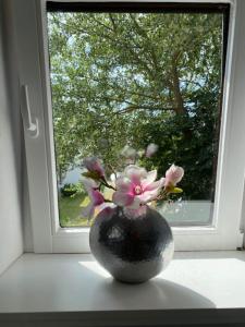eine Vase voller Blumen vor einem Fenster in der Unterkunft Anja in Westerland
