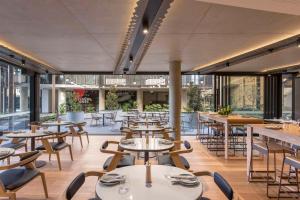 a restaurant with tables and chairs and windows at Vibe Hotel Adelaide in Adelaide