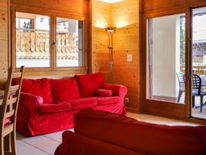 a living room with a red couch and windows at Apartment Les Cimes Blanches 102 A by Interhome in Nendaz