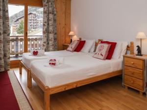 ein Schlafzimmer mit einem großen Bett mit weißer Bettwäsche und roten Kissen in der Unterkunft Apartment Les Etagnes 2est by Interhome in Nendaz