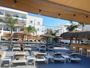 un gruppo di sedie a sdraio e ombrelloni accanto alla piscina di Hotel Chevy & Suites a Cala Ratjada