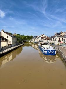 a blue and white boat in a river with houses at Ô Centre- Chaleureux - Fibre - Netflix in Montargis