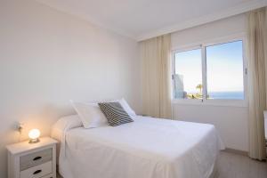 een witte slaapkamer met een bed en een raam bij Cosy flat with sea views in Santa Ursula in Santa Úrsula