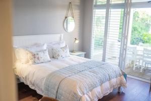 een witte slaapkamer met een bed met kussens bij Sole Haven in Southbroom