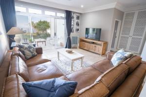 a living room with a brown couch and a television at Sole Haven in Southbroom