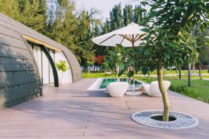 un patio con un árbol, una sombrilla y una piscina en Đầu Rồng Resort, 