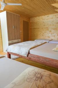 Hakuna Matata Lake House في يايتشه: غرفة نوم بسريرين وجدار خشبي