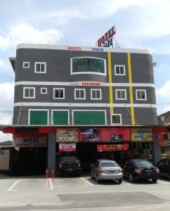 a building with cars parked in a parking lot at Hotel Pinji in Ipoh