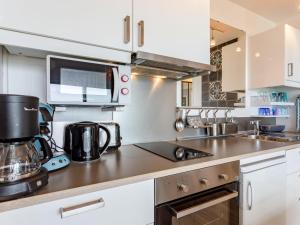 a kitchen with white cabinets and a coffee maker at Apartment La Bizontine-9 by Interhome in Cabourg