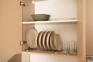 a cupboard with plates and glasses on it at Plakoures Home in Kounoupidhianá