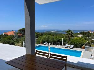 a patio with a wooden table and chairs next to a swimming pool at Dela in Hvar