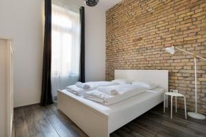 a bedroom with a white bed with a brick wall at J26 Jósika Apartment in Budapest