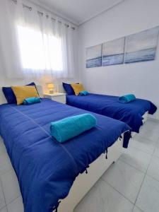 2 camas con almohadas azules en una habitación en Sunny Apartment Costa Blanca, en La Mata