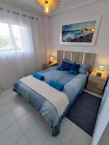 a bedroom with a large bed with blue pillows at Sunny Apartment Costa Blanca in La Mata