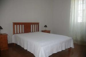 a bedroom with a white bed and two windows at Residência Teresinha in Povoação