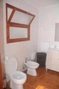 a bathroom with a white toilet and a sink at Residência Teresinha in Povoação +19 photos