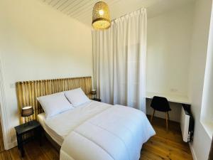 een slaapkamer met een wit bed en een kroonluchter bij Maison des années 1920 - à 150 m de l'océan et proche des commodités - 4 logements indépendants in Saint-Jean-de-Monts