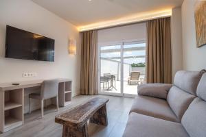 Aljarafe Suites by QHotels في Gelves: غرفة معيشة مع أريكة ومكتب مع تلفزيون