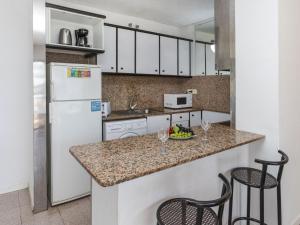 uma cozinha com um frigorífico branco e 2 bancos de bar em Apartment Riviera Park-7 by Interhome em Salou