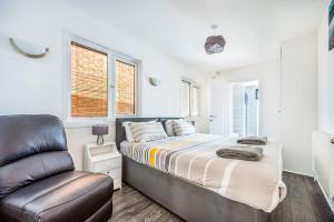 een slaapkamer met een bed en een leren stoel bij Beachfront Escape Sleeps 8 Ideal Family Retreat in Pevensey
