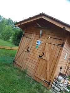 a wooden shed with a door with a sign on it at Szałas, Namiot w Górach Izerskich, agroturystyka, ogrzewanie, klimatyzacja , plac zabaw, ognisko z rusztem i kijkami, żywe zwierzęta, latem basen in Mirsk
